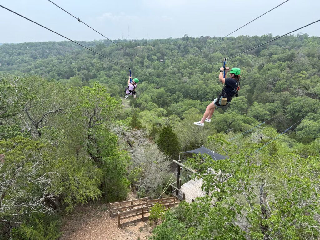 Two people enjoying a ziplining adventure at Zip Lost Pines