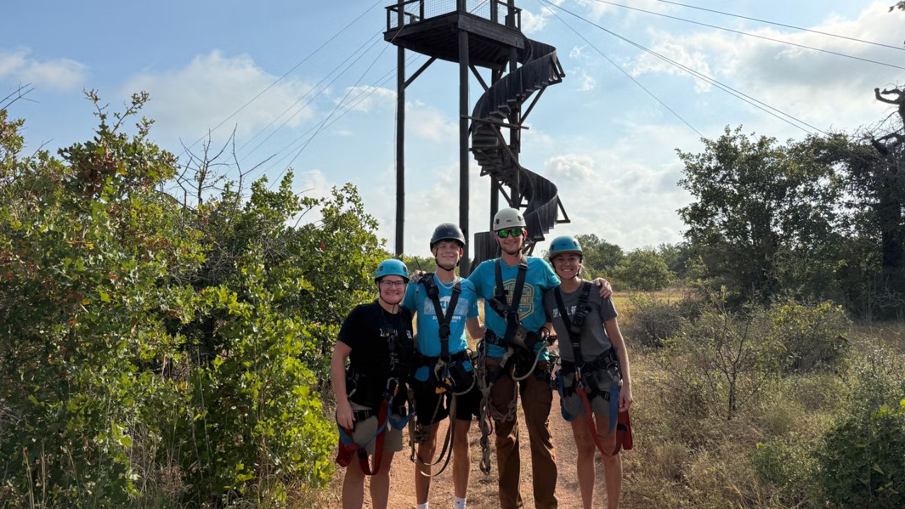 Family wearing helmets and harnesses posing together before a zipline adventure.