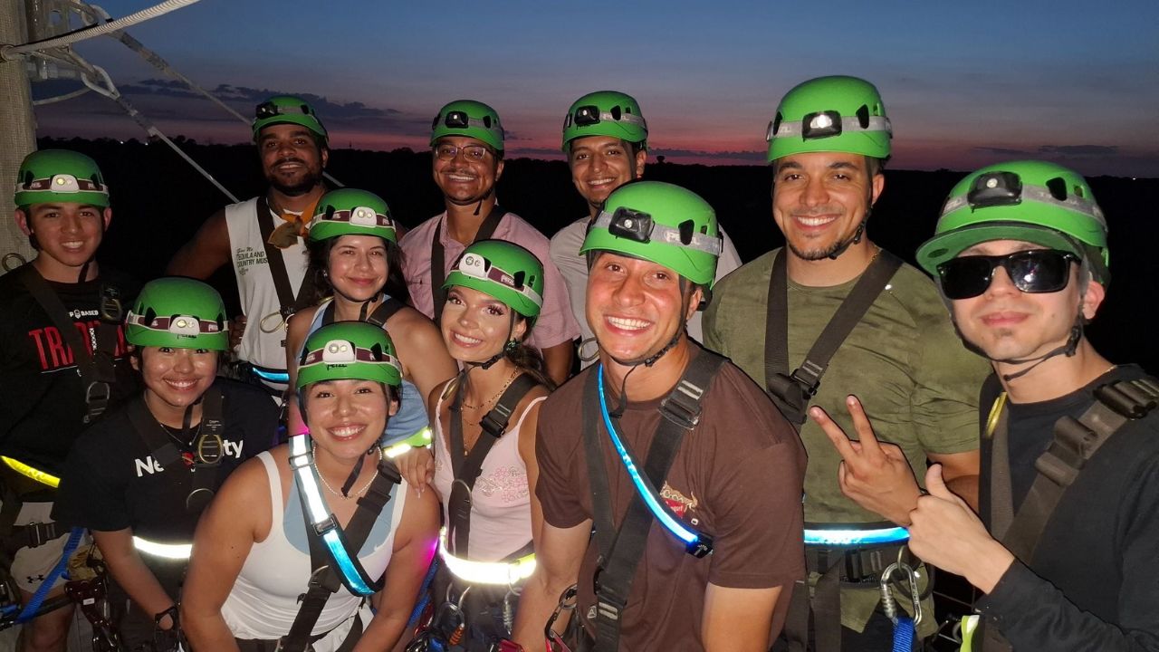 Group posing in zipline gear at night at Zip Lost Pines